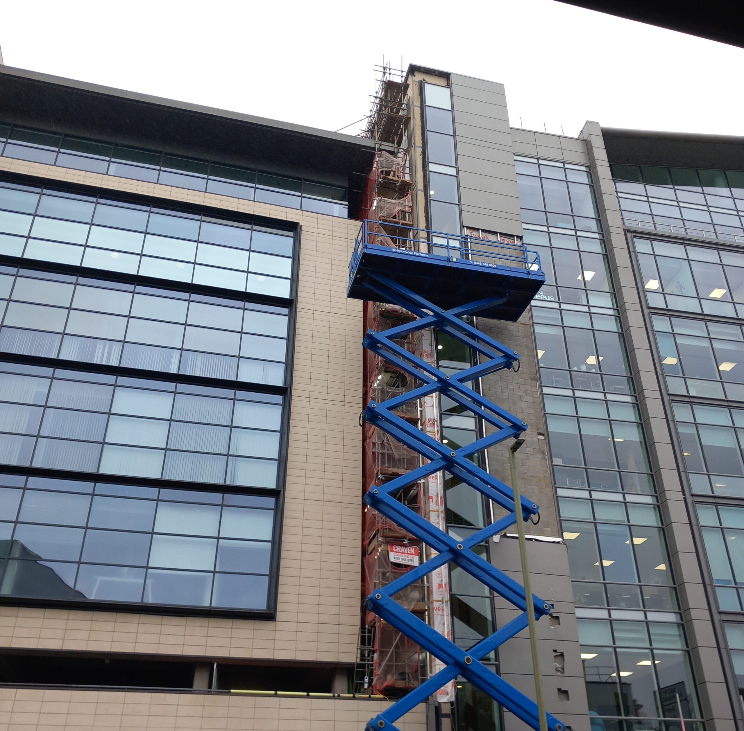 Cladding remediation installation with scissor lift on a modern facade